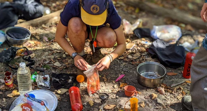 a student prepares food while on a backpacking course with outward bound